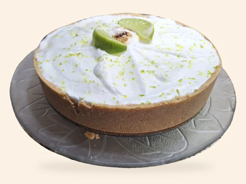Torta de Limão com base dourada, cobertura branca, raspas e gomos de limão